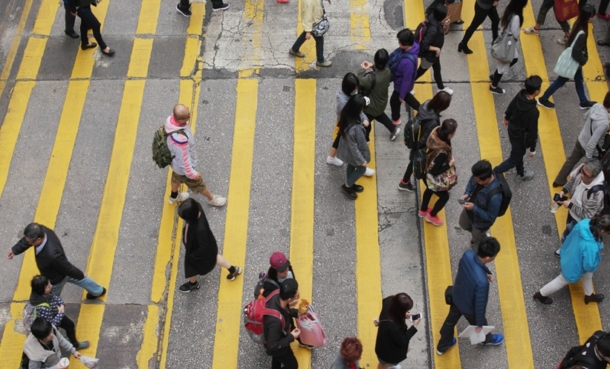 People crossing a city street, representing socioeconomic factors linked to lung cancer risk in never-smokers.