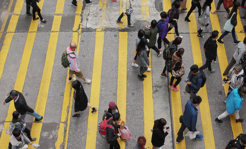 People crossing a city street, representing socioeconomic factors linked to lung cancer risk in never-smokers.