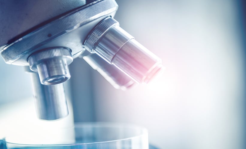 Close up of a laboratory microscope lens with bright light, representing blood cancer and acute erythroid leukemia research.