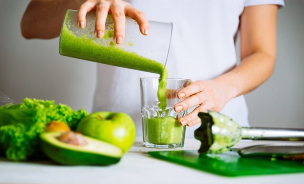 Woman pouring green smoothie as a microbiota-friendly diet concept linked to gut microbiota score and gynecologic cancer risk.
