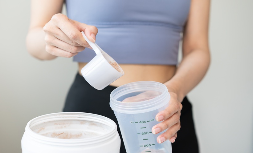 Woman mixing creatine monohydrate powder in a shaker bottle, supplement safety concept