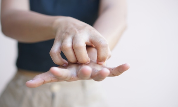 Person scratching an itchy palm, representing plaque psoriasis itching and skin inflammation