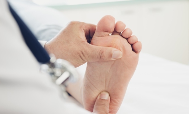 Clinician assessing foot pain in rheumatology podiatry service visit