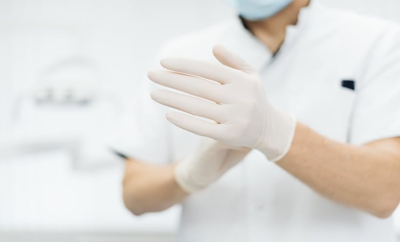 Close-up of a healthcare professional putting on protective medical gloves during an infectious disease clinic examination.