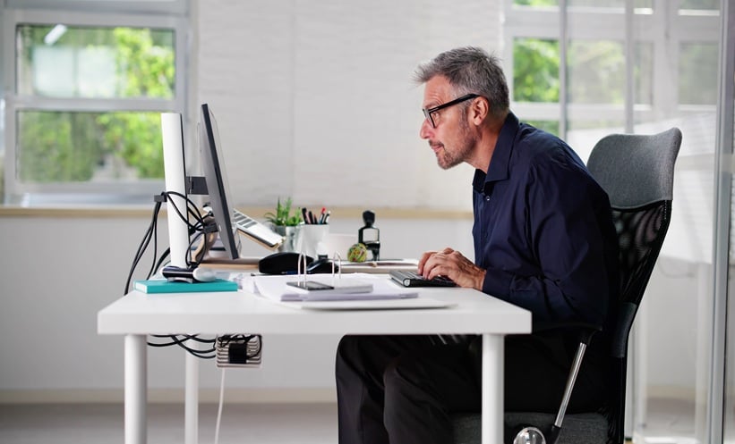 Man with bad posture sitting in office chair at computer desk