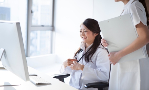 Female doctors and nurses reviewing information on a desktop computer in a clinical setting