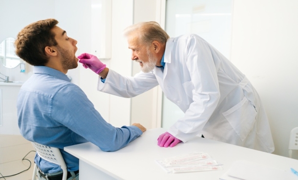 Doctor collecting an oral swab sample from a patient in a clinical setting for pulmonary tuberculosis testing
