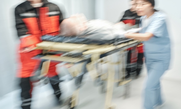 Blurred hospital scene showing emergency responders and a nurse rushing a patient on a stretcher, illustrating acute stroke emergency care.
