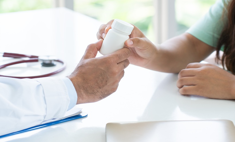 Close-up of physician giving medication bottle to patient during consultation