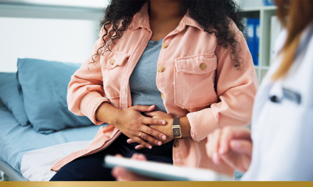 A women sitting next to a doctor clutching her abdomen