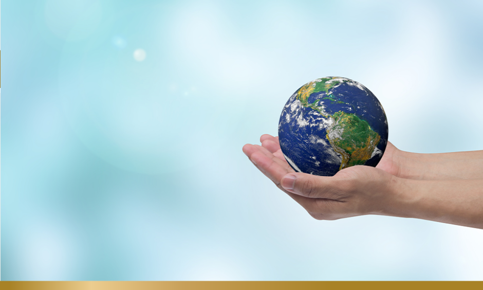 Hands holding model of a globe on a blue background