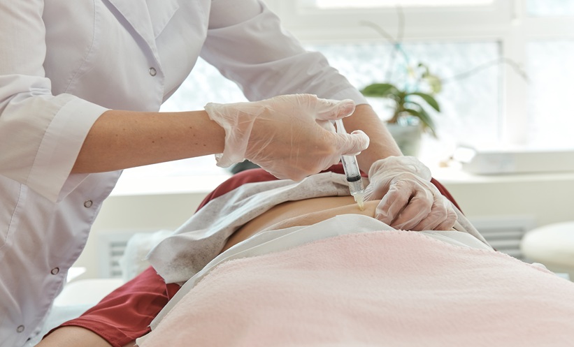 Patient lying down while a doctor delivers a clear injection on their abdomen.