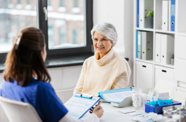 Older woman in consultation with a clinician discussing women’s health treatment options in a medical office.