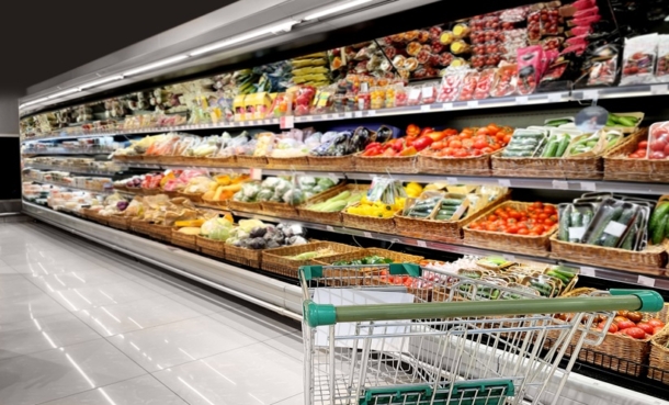 Shopper comparing packaged food labels in a supermarket aisle to understand ultra-processed foods