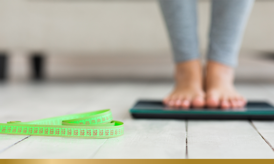 Person standing on scale, with tape measure on the floor