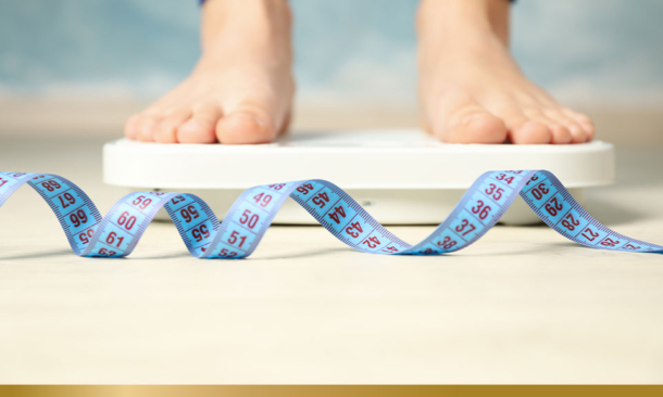 Person's feet standing on scales with tape measure in front on the floor