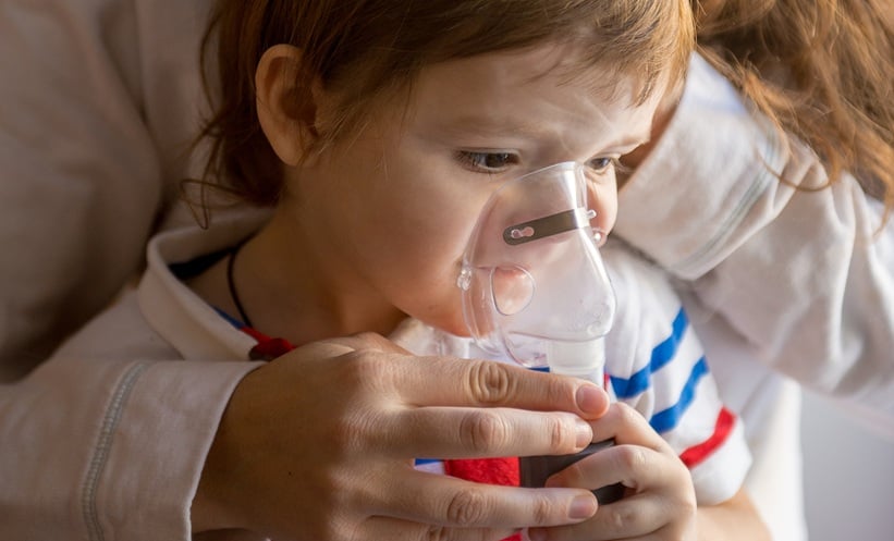 Preschool child receiving respiratory treatment for acute wheezing symptoms