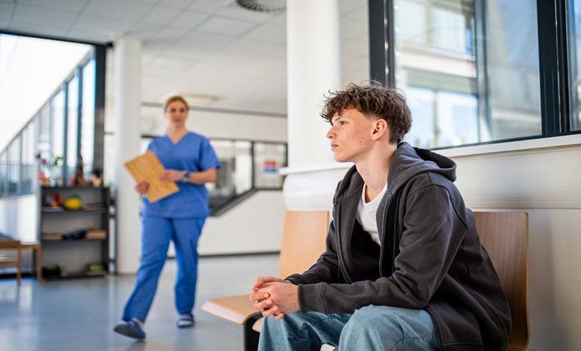 Young adults in a clinic waiting room representing gonorrhea vaccine access and migrant sexual health services.