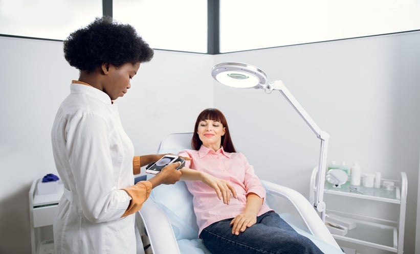 Dermatology clinician performing a skin cancer screening examination for a patient.