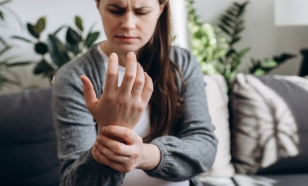 Patient holding wrist during psoriatic arthritis flare and treatment discussion