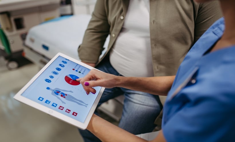 Doctor discussing obesity and lung cancer survival data with a patient in a clinical consultation.