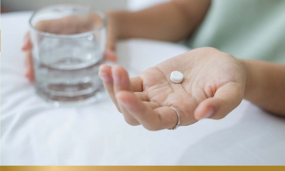 Person holding a single pill in their hand