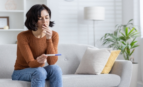 Woman looking disappointedly at a pregnancy test