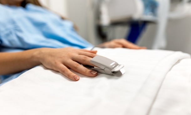 Adult patient in hospital bed with pulse oximeter during respiratory infection monitoring.