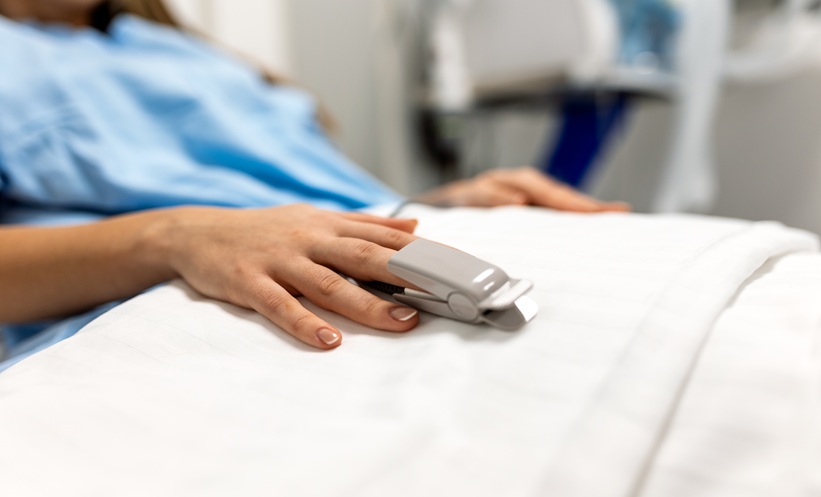 Adult patient in hospital bed with pulse oximeter during respiratory infection monitoring.