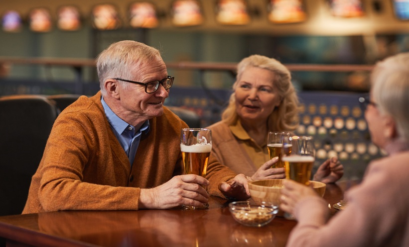 Older adults drinking beer together in a bar, illustrating alcohol consumption and dementia risk in steatotic liver disease.
