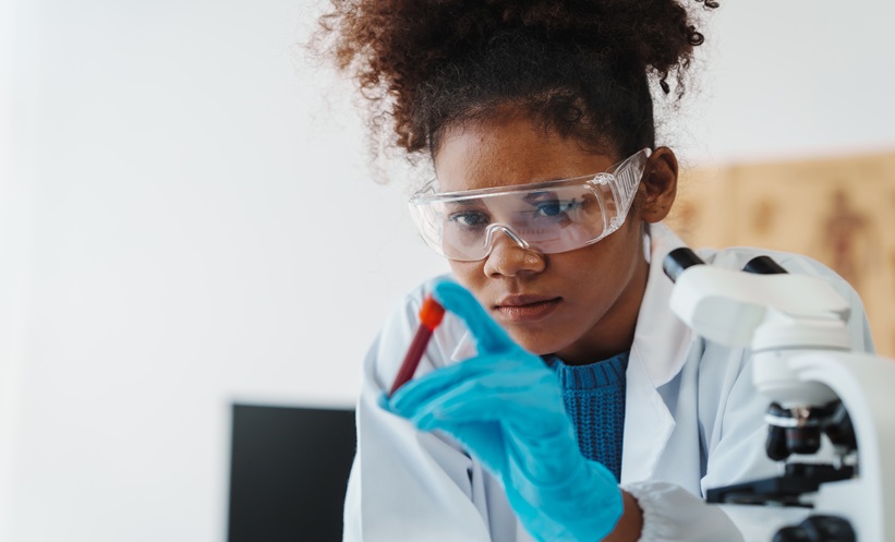 Female researcher examining a blood sample in a laboratory, representing bloodstream infection diagnosis and antimicrobial research.