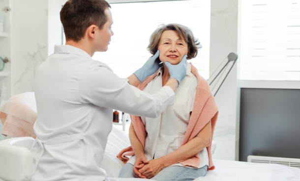 Dermatologist examining a patient during consultation for inflammatory skin symptoms