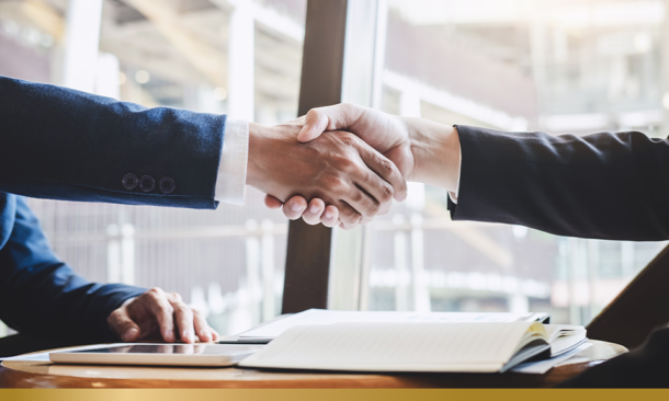 Two people shaking hands over a desk