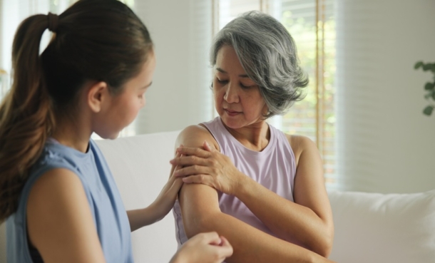 adult applying cream on elderly mother
