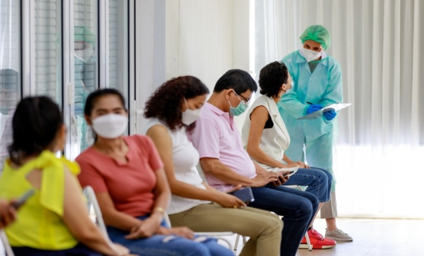 Nurse enters room with many patients waiting.
