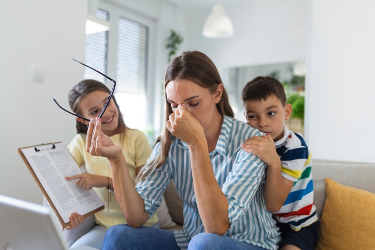 Upset mother having problem with noisy naughty daughter and son jumping on couch and screaming, demanding attention