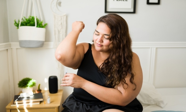 A larger woman gives herself a shot of GLP-1