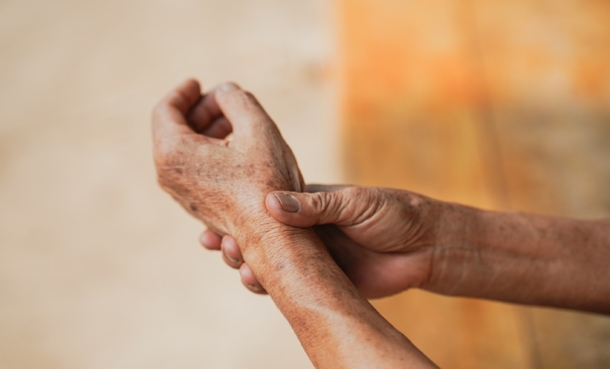 Senior woman holding his painful wrist with arthritis inflammation.
