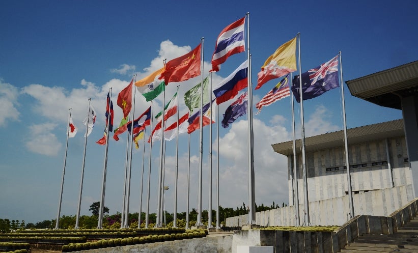 Many different international flags stand waving in the wind.
