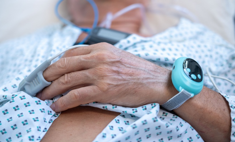 Man undergoing sleep apnea monitoring with a fingertip pulse oximeter and wearable sleep device.