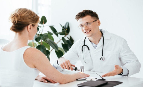 Dermatologist examining a patient receiving follow-up care for resected melanoma