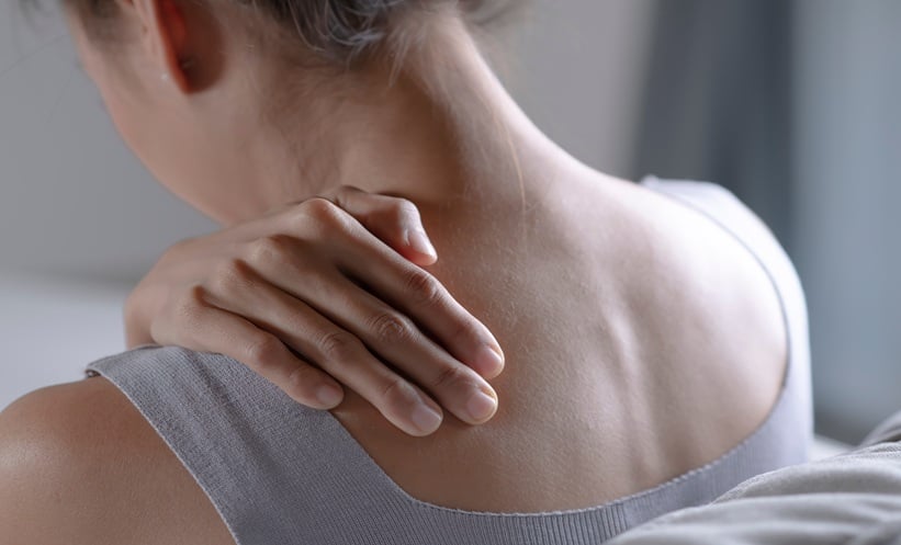 woman rubbing shoulders to soothe pain from fibromyalgia