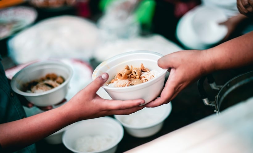 Hands exchanging a bowl of food, symbolizing humanitarian support for displaced persons.