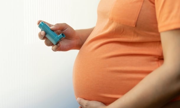Pregnant woman using an inhaler as part of asthma treatment during pregnancy.