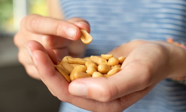 person holds out a handful of peanuts