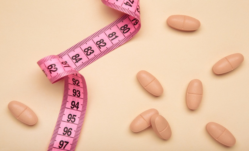 Measuring tape and pills scattered on a table