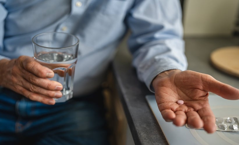 A person about to take a pill with a glass of water