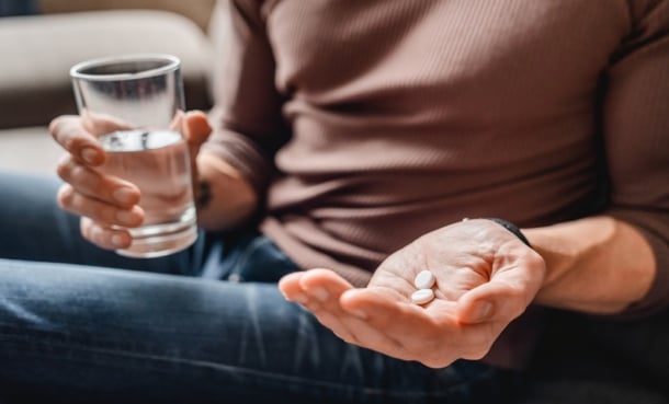Close up of man taking cancer pills with water