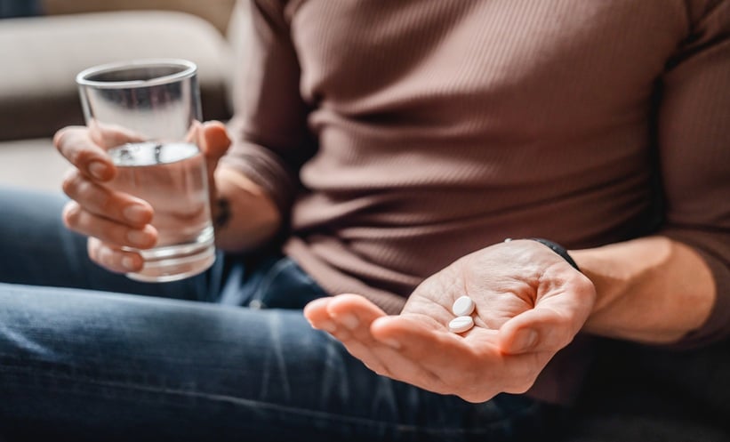 Close up of man taking cancer pills with water