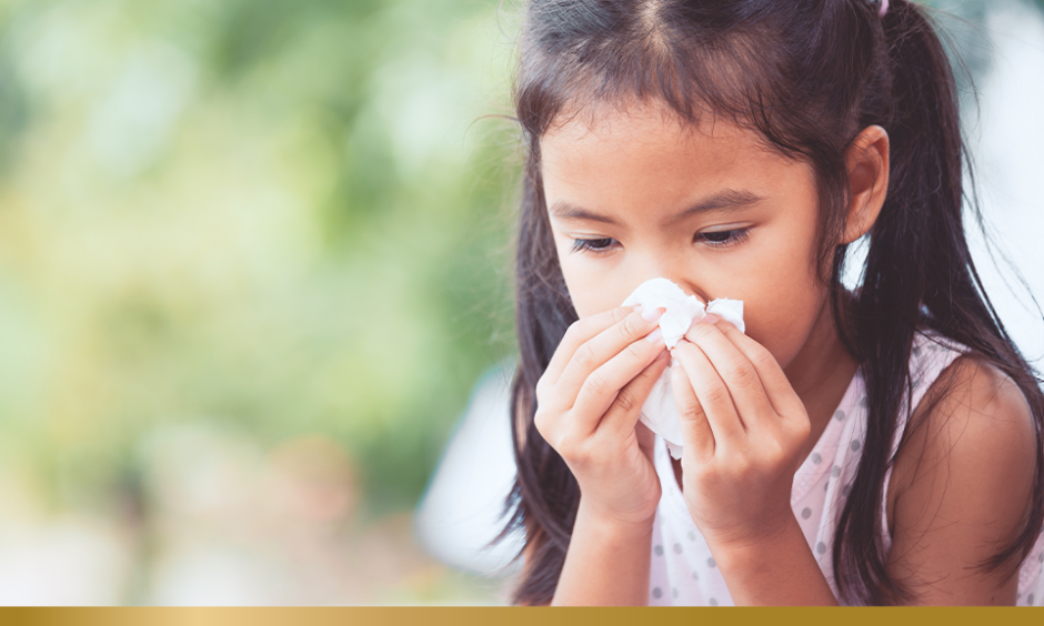 Young child blowing her nose into a tissue